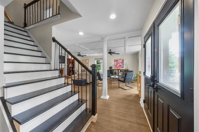 foyer with decorative columns, ceiling fan, and light wood-type flooring