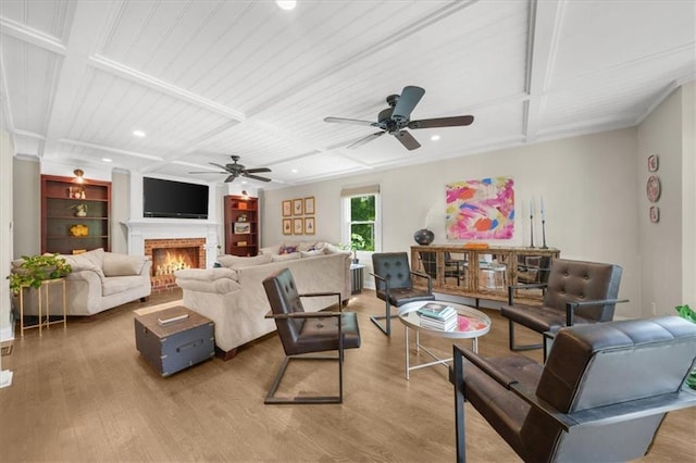 living room featuring ceiling fan, a fireplace, wood-type flooring, and coffered ceiling