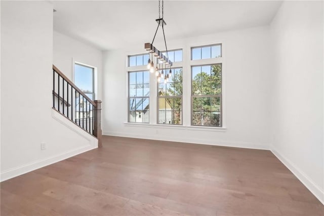 unfurnished dining area with dark hardwood / wood-style floors, an inviting chandelier, and a healthy amount of sunlight