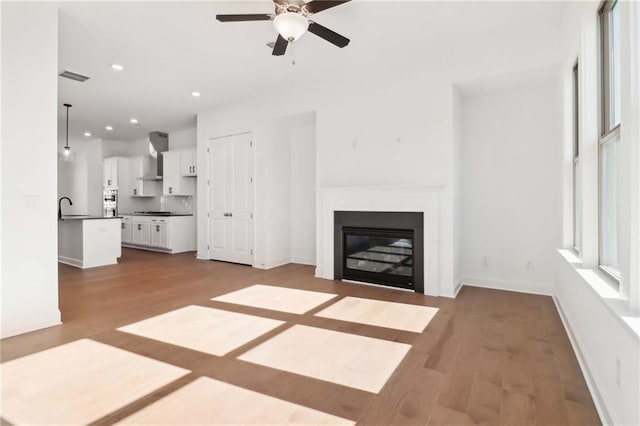 unfurnished living room featuring ceiling fan, light hardwood / wood-style flooring, and sink