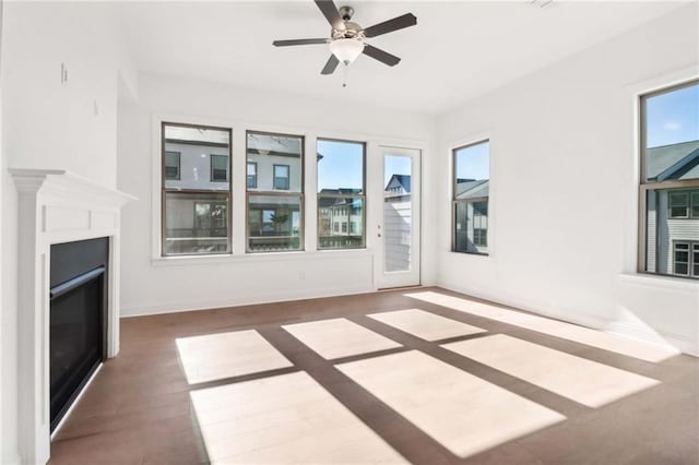 unfurnished living room featuring dark hardwood / wood-style flooring, ceiling fan, and a healthy amount of sunlight