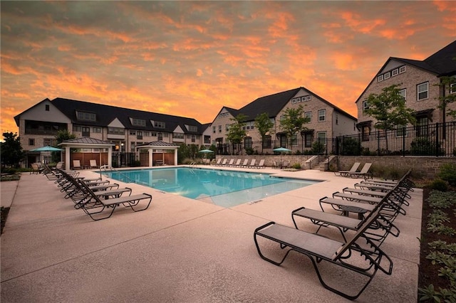 pool at dusk featuring a gazebo and a patio