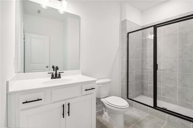 bathroom featuring tile patterned flooring, vanity, toilet, and walk in shower