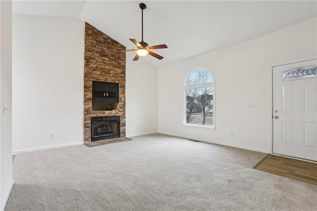 unfurnished living room featuring baseboards, a stone fireplace, ceiling fan, and carpet flooring