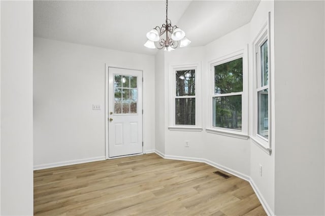 interior space featuring visible vents, lofted ceiling, an inviting chandelier, light wood finished floors, and baseboards