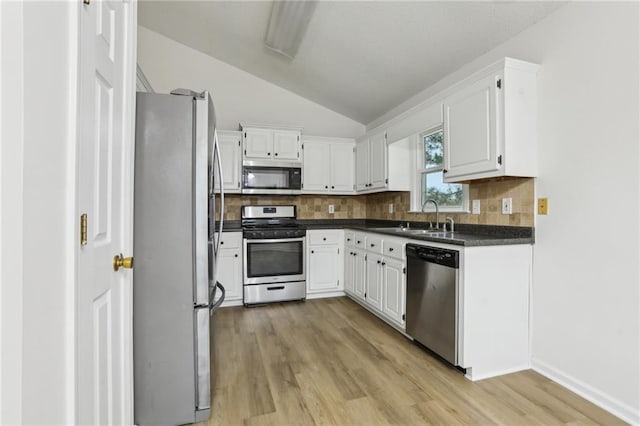 kitchen featuring a sink, stainless steel appliances, white cabinets, dark countertops, and backsplash