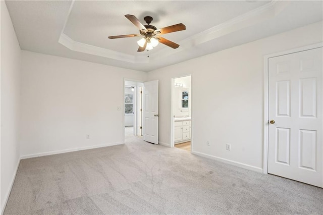 unfurnished bedroom featuring light colored carpet, crown molding, a raised ceiling, and baseboards