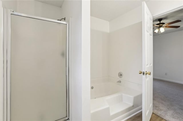 bathroom with baseboards, a stall shower, a ceiling fan, and a garden tub