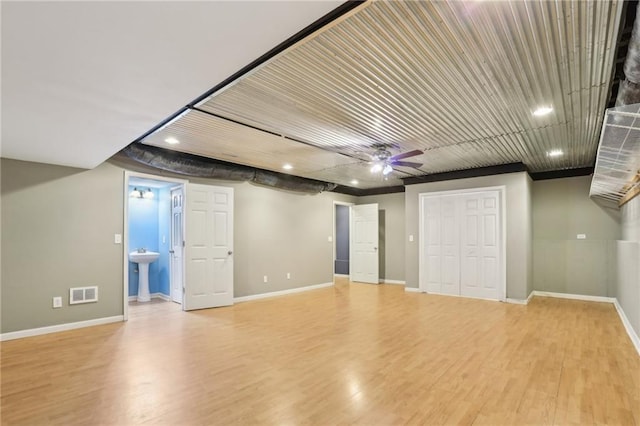 interior space with a sink, visible vents, baseboards, and light wood finished floors