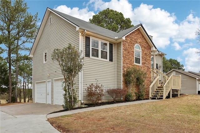 view of side of property with stairway, driveway, a garage, stone siding, and a lawn