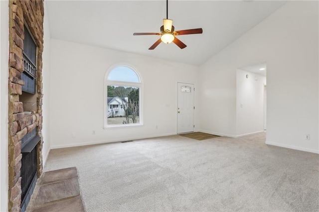 unfurnished living room with high vaulted ceiling, a ceiling fan, carpet, a stone fireplace, and baseboards