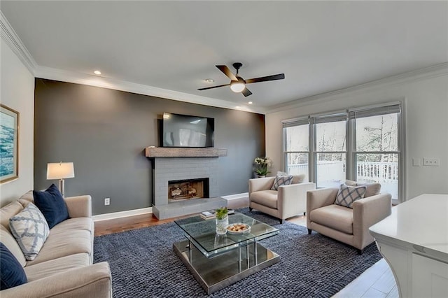 living room featuring ceiling fan, ornamental molding, a brick fireplace, and hardwood / wood-style floors