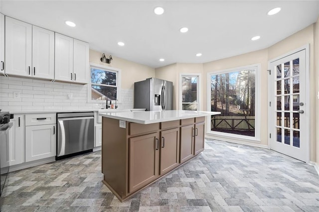 kitchen with white cabinets, sink, decorative backsplash, appliances with stainless steel finishes, and a kitchen island