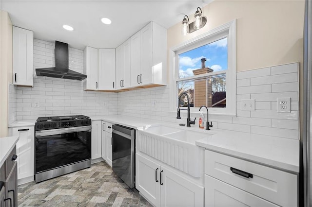 kitchen with light stone countertops, white cabinetry, stainless steel appliances, wall chimney range hood, and decorative backsplash