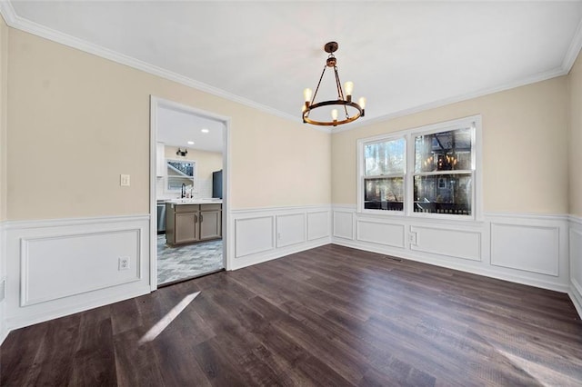 unfurnished dining area featuring dark hardwood / wood-style flooring, crown molding, a notable chandelier, and sink