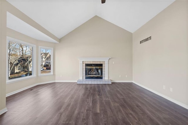 unfurnished living room featuring dark hardwood / wood-style flooring, vaulted ceiling, and a tiled fireplace