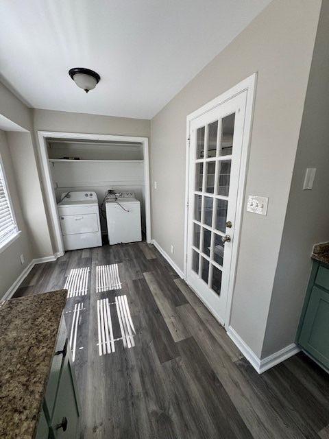 laundry area featuring laundry area, baseboards, dark wood-type flooring, and washer and clothes dryer