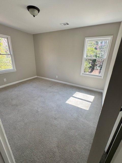 carpeted spare room featuring visible vents and baseboards