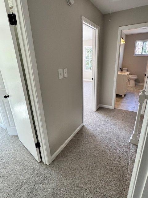 hall with baseboards and light carpet