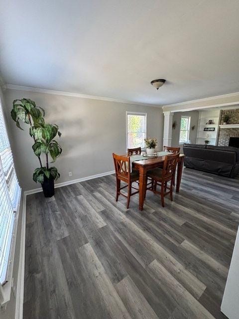 dining space with ornamental molding, a fireplace, baseboards, and wood finished floors