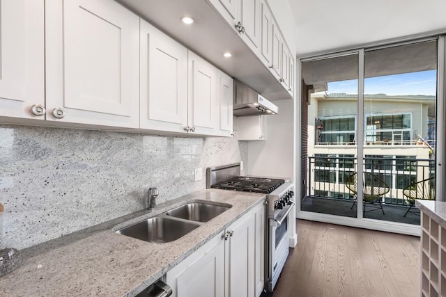 kitchen with extractor fan, white cabinetry, sink, stainless steel stove, and backsplash