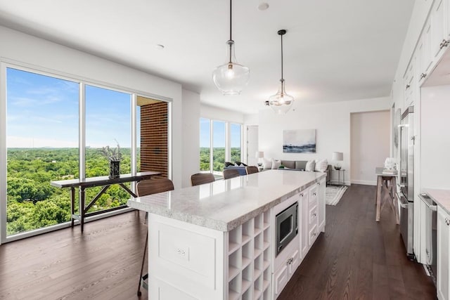 kitchen with pendant lighting, a kitchen island, a kitchen bar, white cabinetry, and appliances with stainless steel finishes