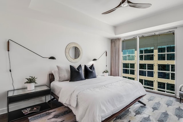 bedroom with ceiling fan, hardwood / wood-style floors, and a tray ceiling