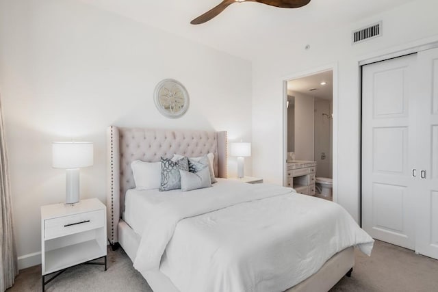 bedroom featuring ceiling fan, light colored carpet, and ensuite bath