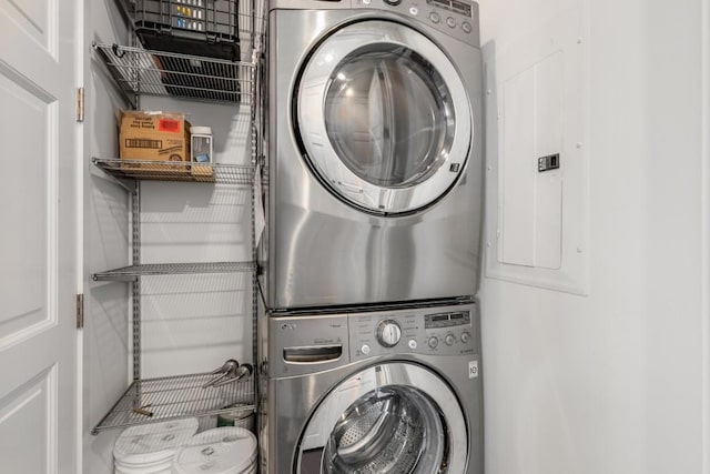 washroom with electric panel and stacked washer and dryer