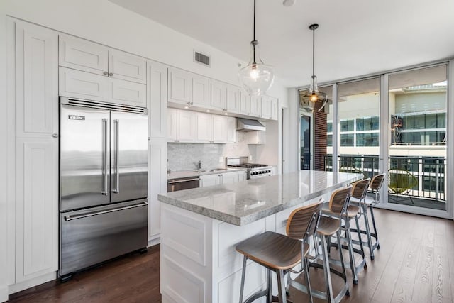 kitchen with appliances with stainless steel finishes, backsplash, decorative light fixtures, light stone countertops, and white cabinets