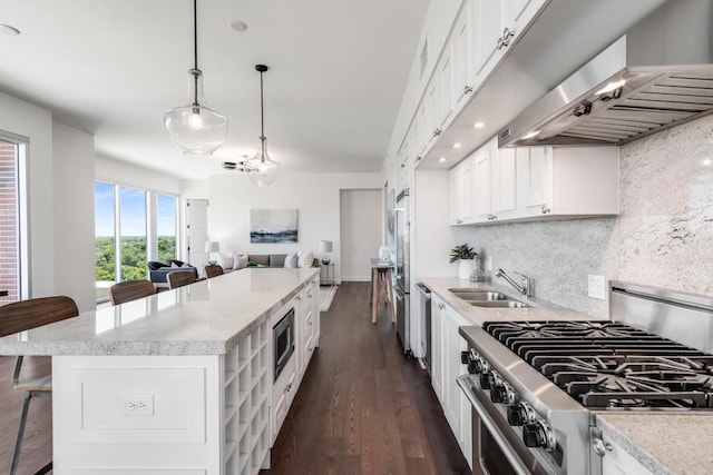 kitchen featuring decorative light fixtures, range hood, a kitchen bar, sink, and high quality appliances