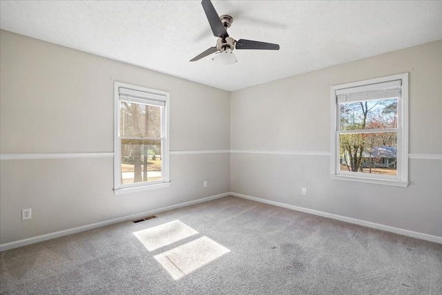 carpeted spare room featuring ceiling fan, baseboards, visible vents, and a textured ceiling