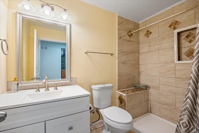 bathroom with visible vents, toilet, tiled shower, and vanity