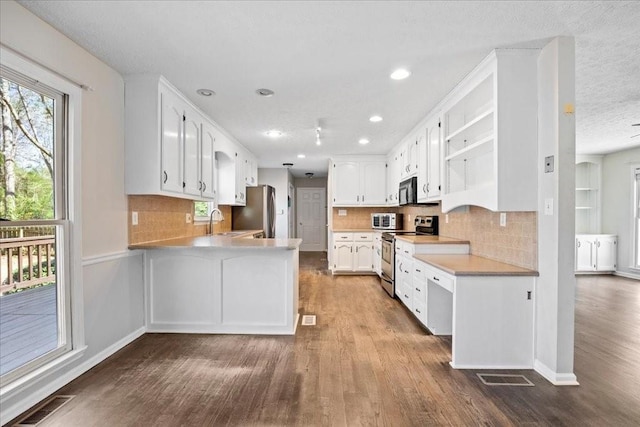 kitchen with visible vents, light countertops, appliances with stainless steel finishes, a peninsula, and open shelves