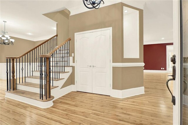 foyer with a notable chandelier, light hardwood / wood-style floors, and crown molding