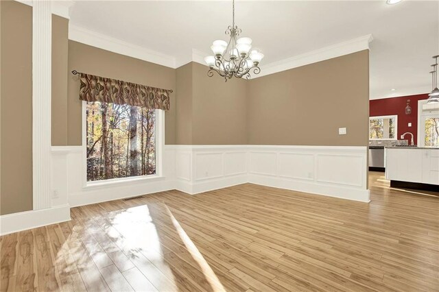 empty room featuring ornamental molding, a notable chandelier, and light wood-type flooring