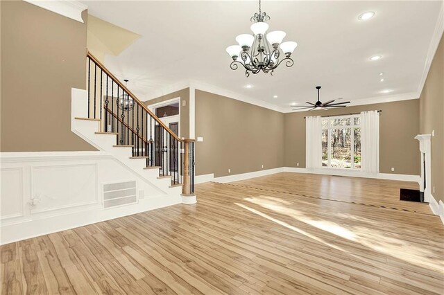 unfurnished living room with ceiling fan with notable chandelier, light hardwood / wood-style flooring, and crown molding