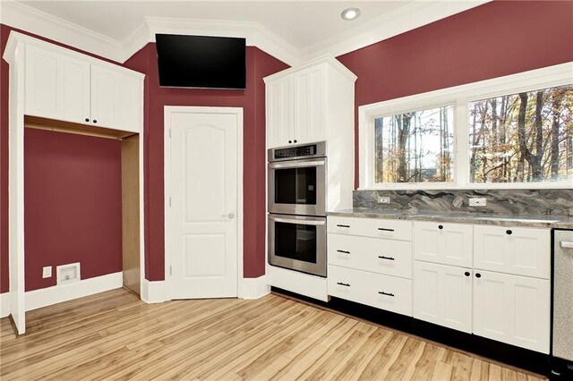 kitchen with backsplash, crown molding, light hardwood / wood-style flooring, appliances with stainless steel finishes, and white cabinetry