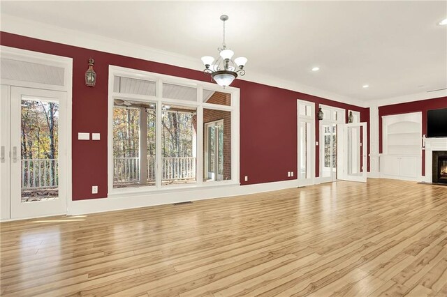 unfurnished living room featuring a chandelier, light wood-type flooring, and a healthy amount of sunlight