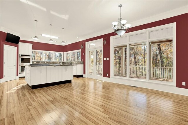 kitchen featuring hanging light fixtures, a kitchen island, double oven, light hardwood / wood-style floors, and white cabinets