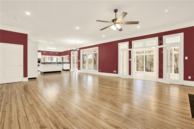 unfurnished living room featuring light hardwood / wood-style floors and ceiling fan with notable chandelier