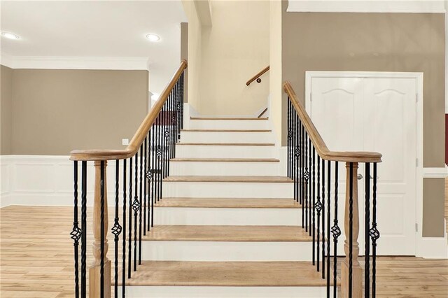 stairway featuring wood-type flooring and ornamental molding