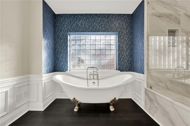 bathroom with hardwood / wood-style flooring and a tub to relax in