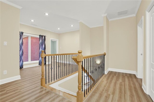 corridor with light hardwood / wood-style floors and ornamental molding