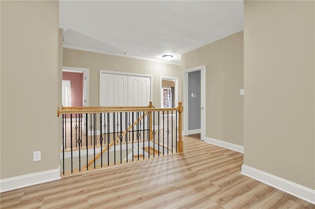 hallway featuring crown molding and light hardwood / wood-style flooring