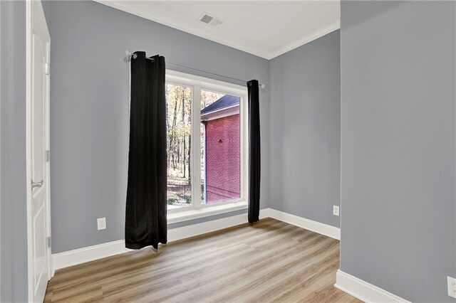 unfurnished room with a wealth of natural light, light hardwood / wood-style flooring, and ornamental molding