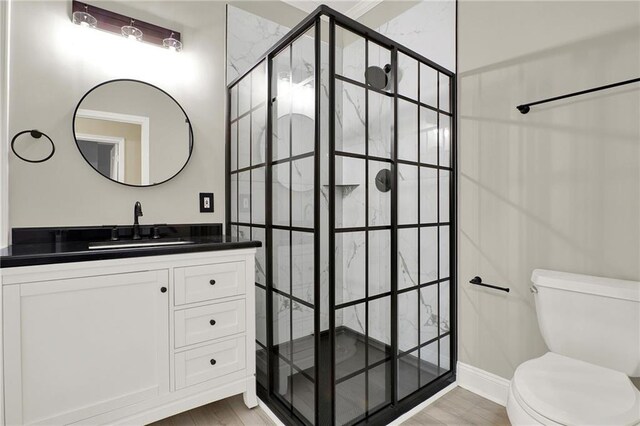 bathroom with tiled shower, vanity, wood-type flooring, and toilet