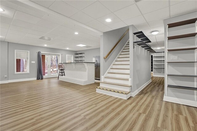 interior space with light hardwood / wood-style floors, stainless steel refrigerator, and a drop ceiling