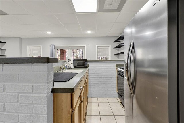 kitchen with light tile patterned flooring, sink, a paneled ceiling, and black appliances