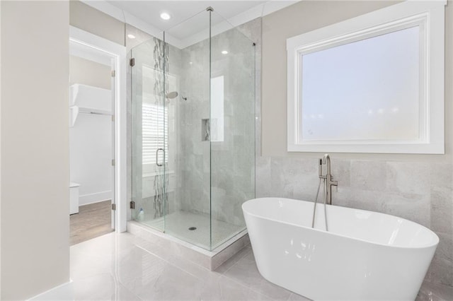 full bathroom featuring a shower stall, recessed lighting, tile walls, and a freestanding bath